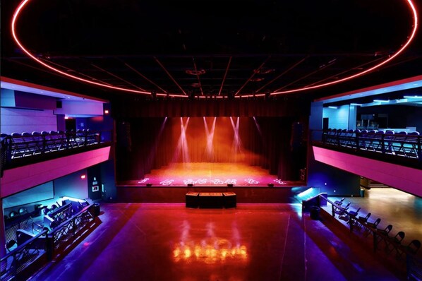 Un teatro con un escenario central, varios balcones y un diseño moderno.