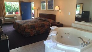 Ein Hotelzimmer mit einem Bett, einer großen Badewanne, einem Schreibtisch und einem Fenster mit Vorhängen.