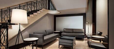 Un salon moderne avec un escalier, un canapé, une table basse et une lampe.