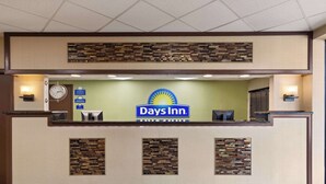 Una recepción con el logotipo de Days Inn, un reloj y un escritorio pequeño con una computadora.