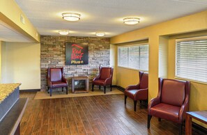 A reception area with a stone wall, a Red Roof Plus sign, and four leather chairs. - Red Roof Inn PLUS+ Washington DC - Manassas (Manassas)