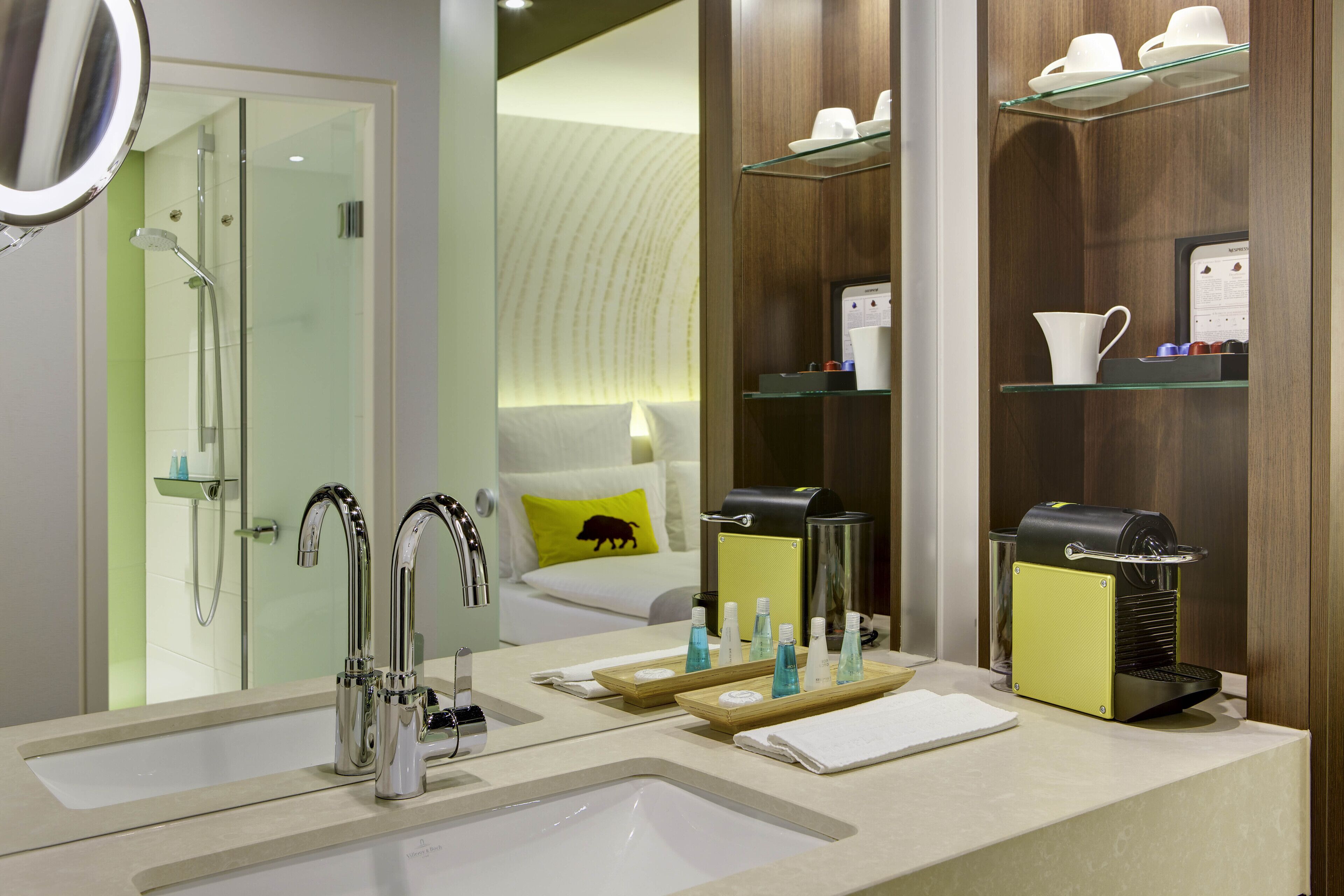 Un baño moderno con lavamanos dobles, cafetera y cabina de ducha de vidrio.