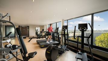 Un gimnasio con cintas de correr, bicicletas estáticas y máquinas de pesas.
