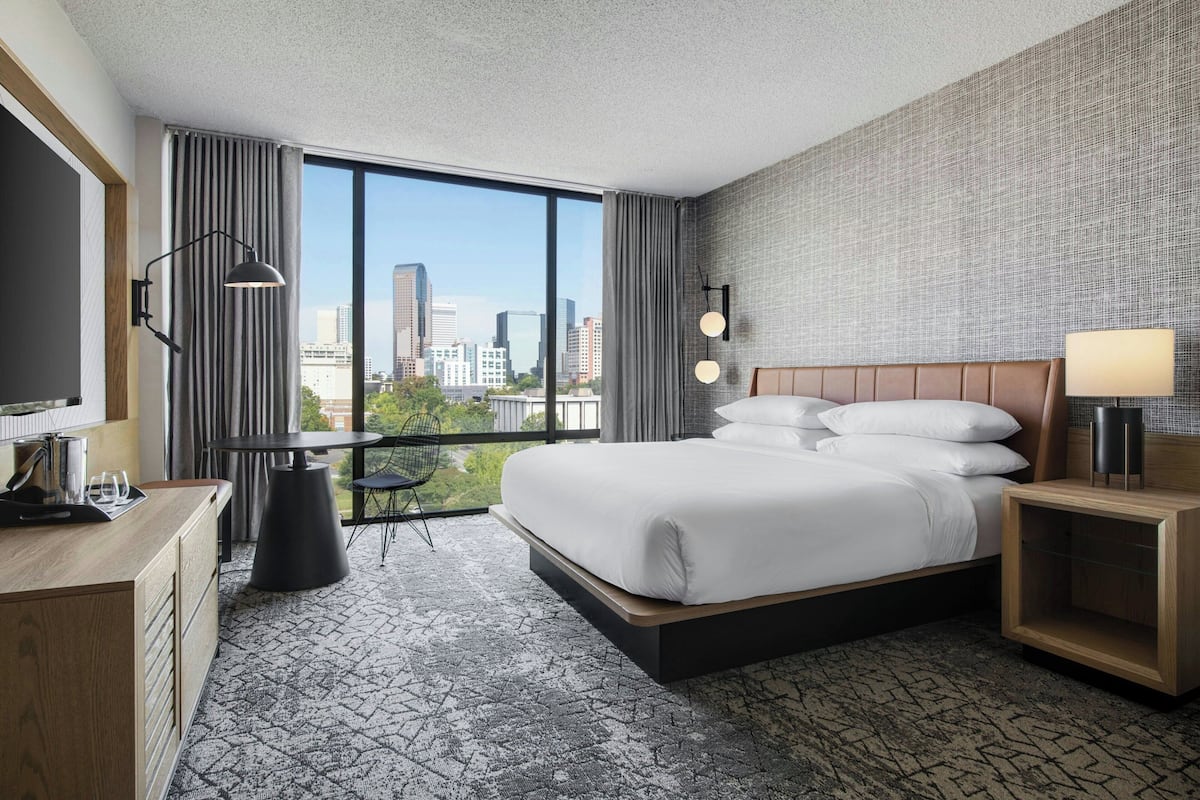 Un hotel moderno con una cama grande, un escritorio, una silla y vistas a la ciudad.