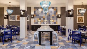 A dining area with a long table, blue chairs, and patterned floor tiles. - Sheraton Charlotte Hotel (Charlotte)