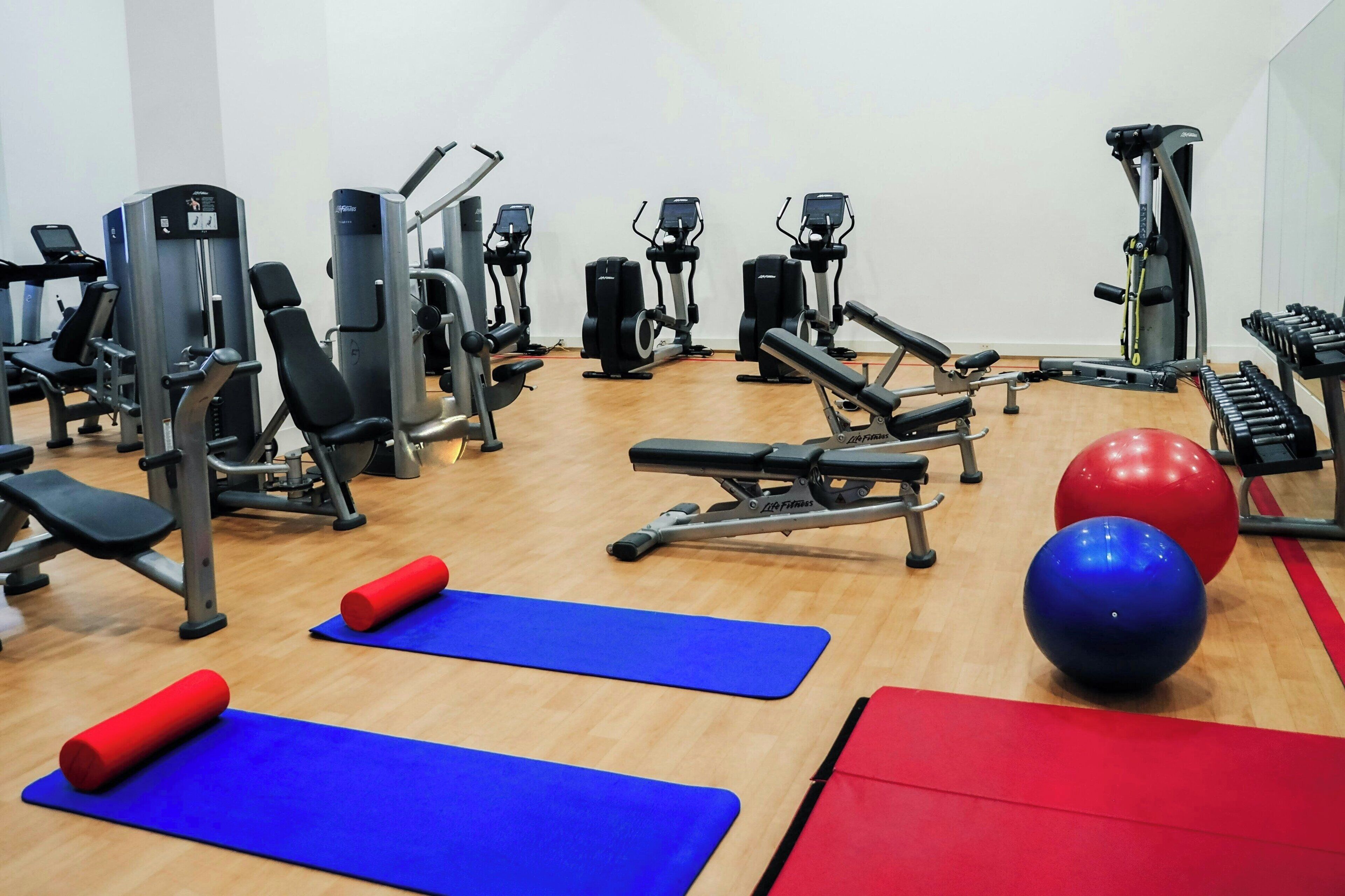 A gym with various exercise equipment, including treadmills, elliptical machines, and free weights.