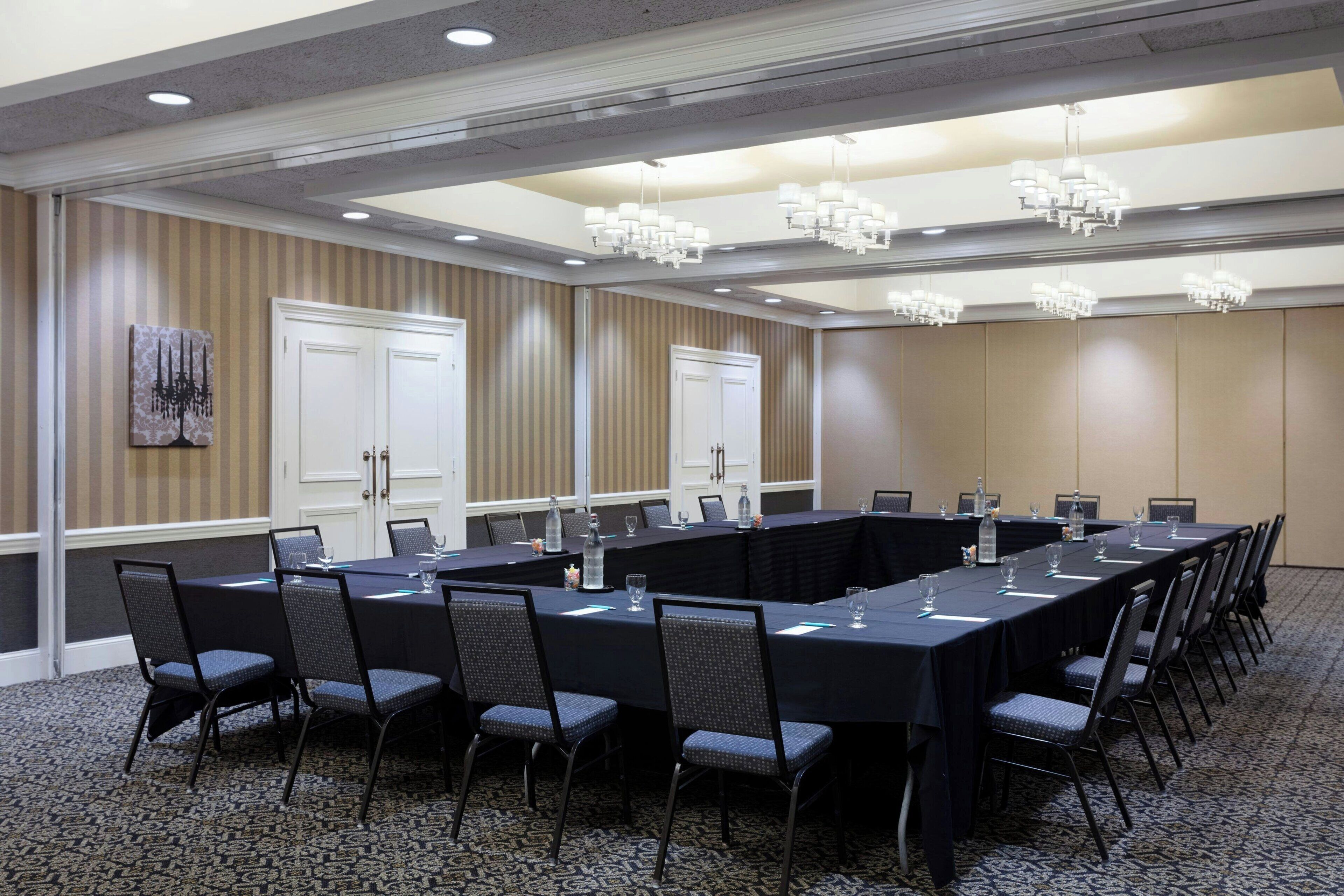 A conference room with a long table, chairs, and chandeliers.