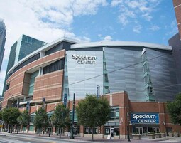 Un edificio de Spectrum Center con un diseño arquitectónico moderno, que destaca por una fachada de vidrio y una estructura curva.