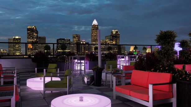 A rooftop terrace with modern seating, a city skyline view, and illuminated tables. - Sheraton Charlotte Hotel (Charlotte)