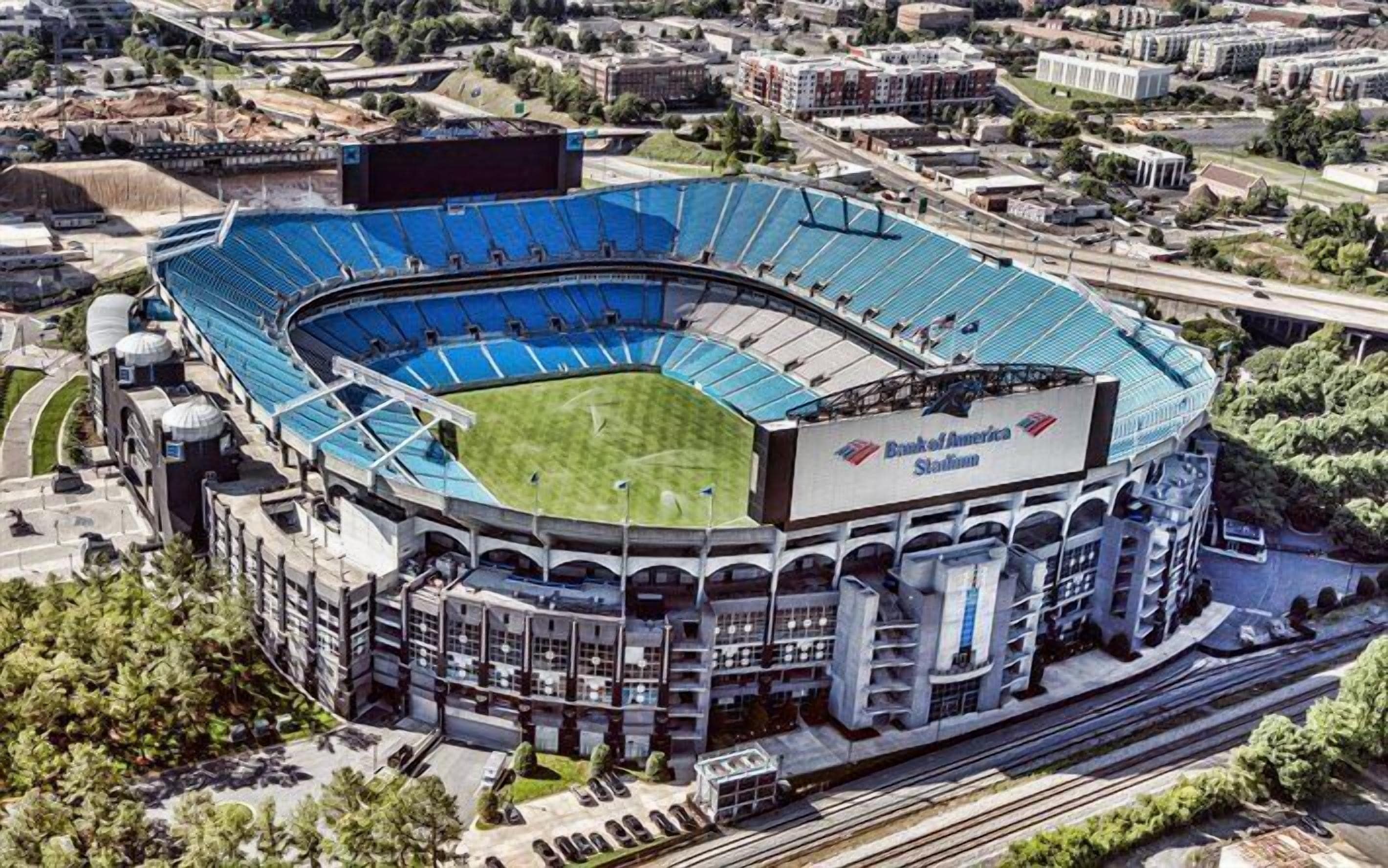A stadium with a curved roof, multiple tiers of seating, and a large field.