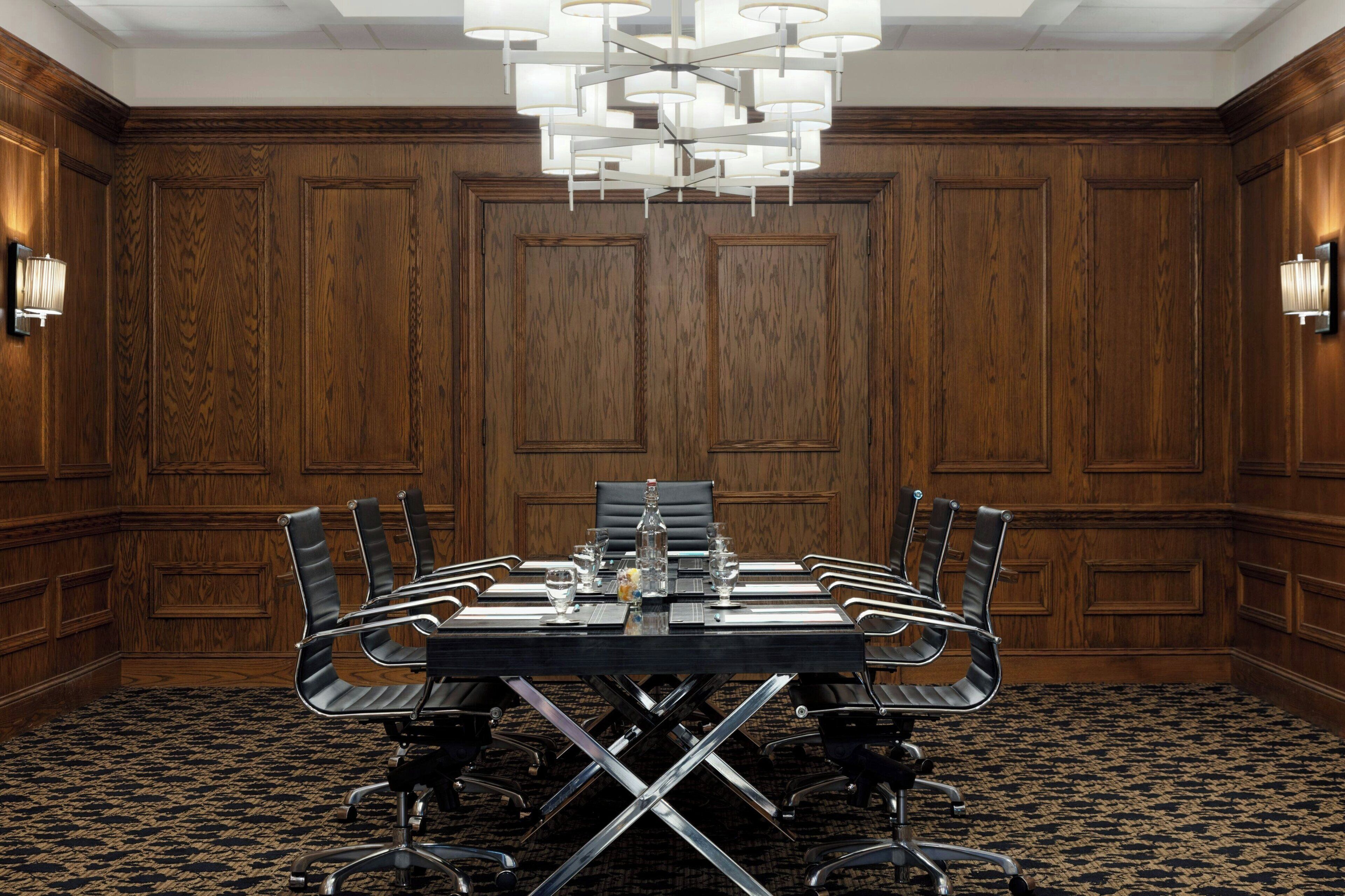 A conference room with a large table, chairs, and a chandelier.