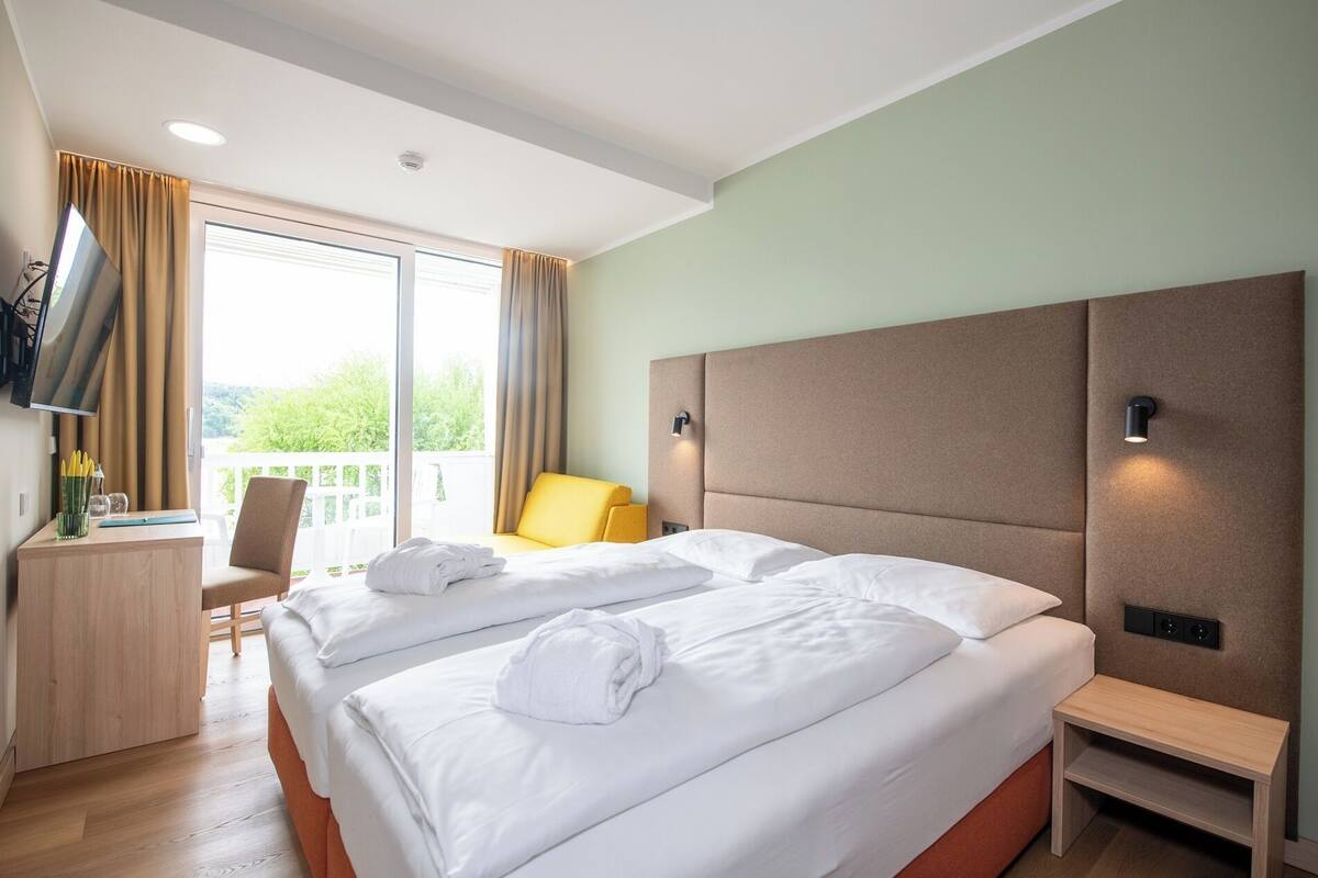 Ein Hotelzimmer mit zwei Betten, einem Schreibtisch, einem Stuhl und einem Fernseher.