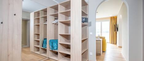 A modern apartment with a large walk-in closet, a yellow sofa, and a view through an archway.