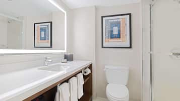 Un baño moderno con un espejo grande, dos lavamanos, un inodoro y una cabina de ducha de vidrio.