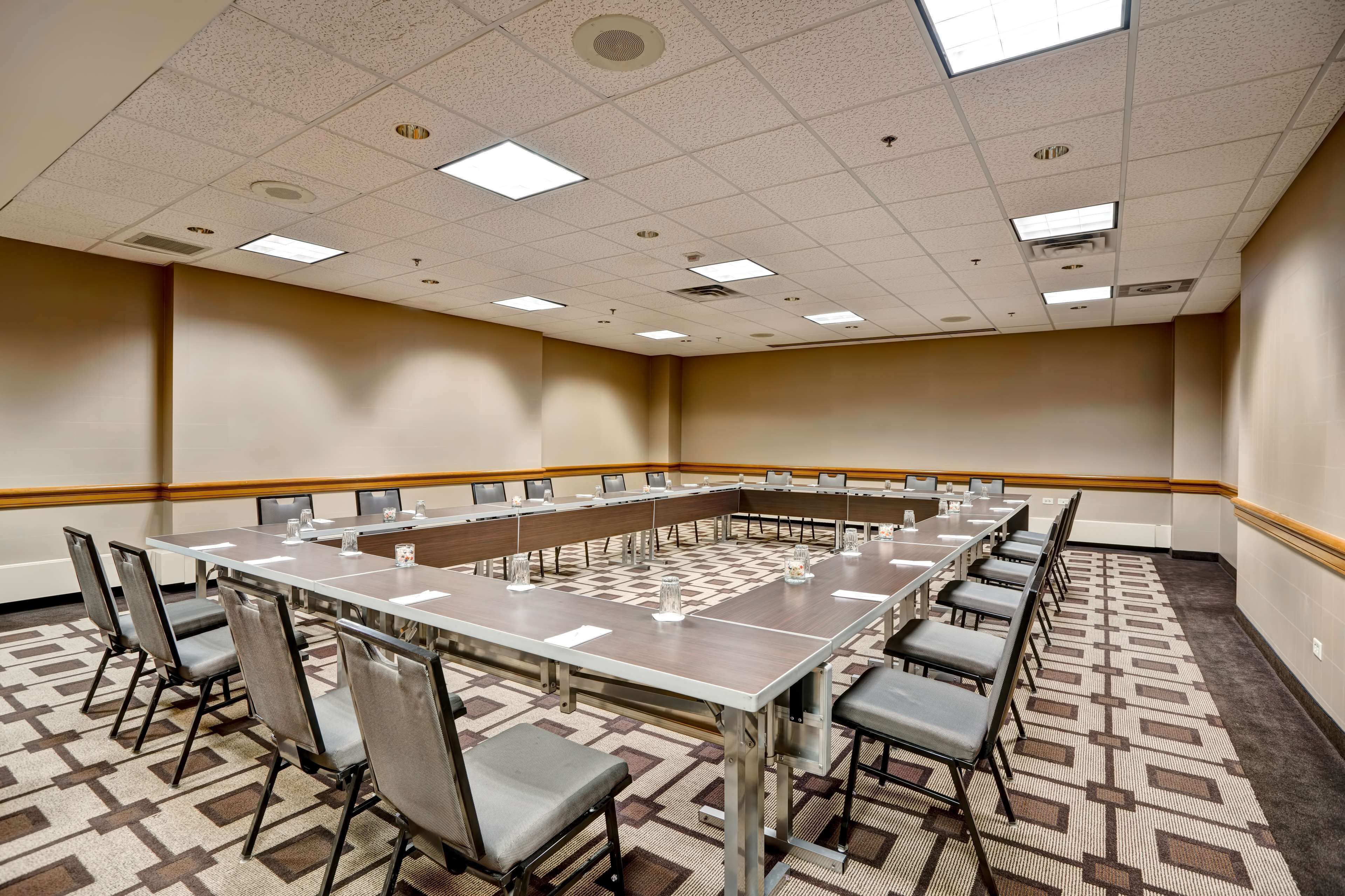 A conference room with a long table, chairs, and a patterned carpet.