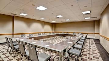 A conference room with a long table, chairs, and a patterned carpet.