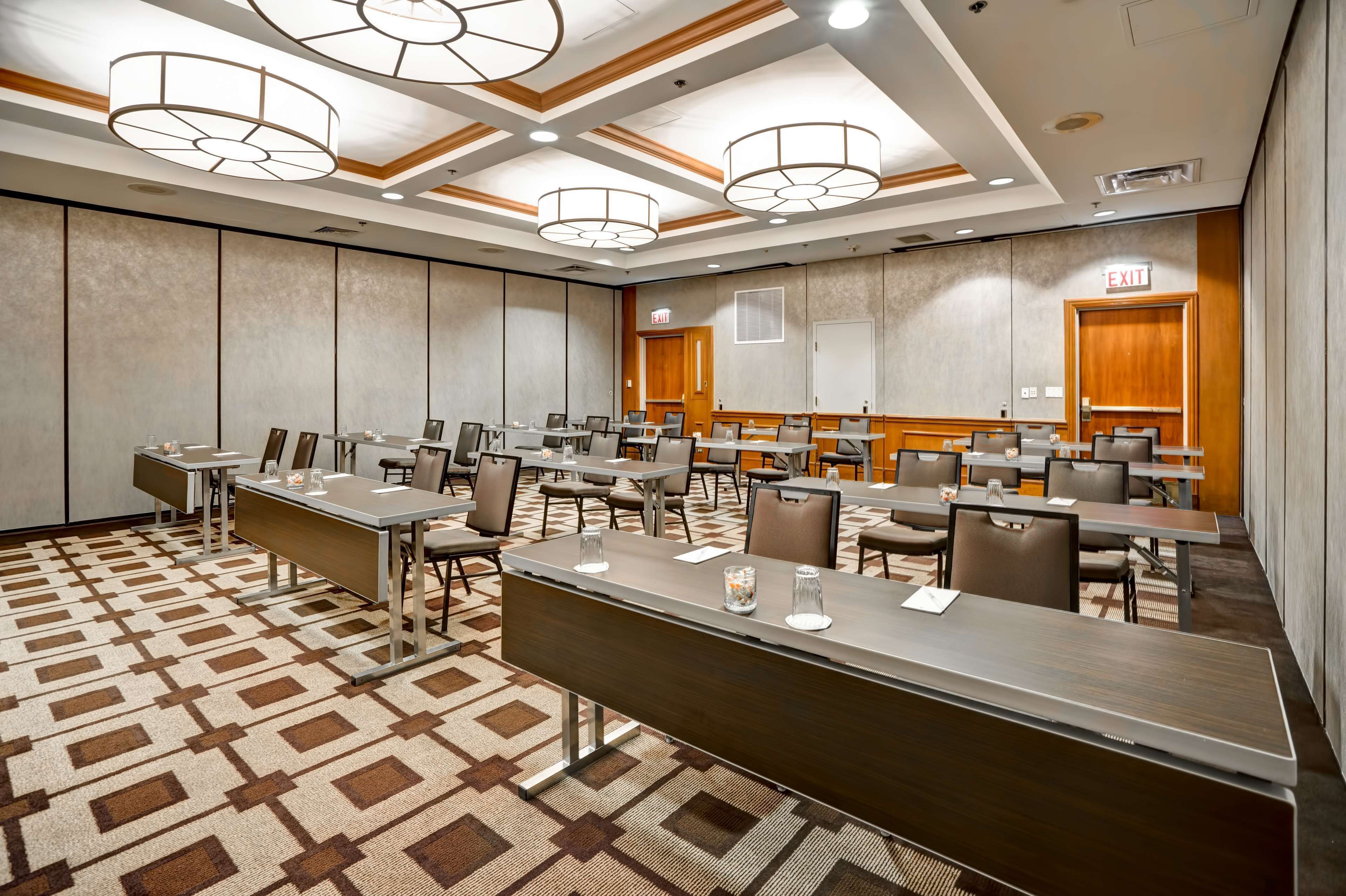 A conference room with multiple tables and chairs, a patterned carpet, and ceiling lights.