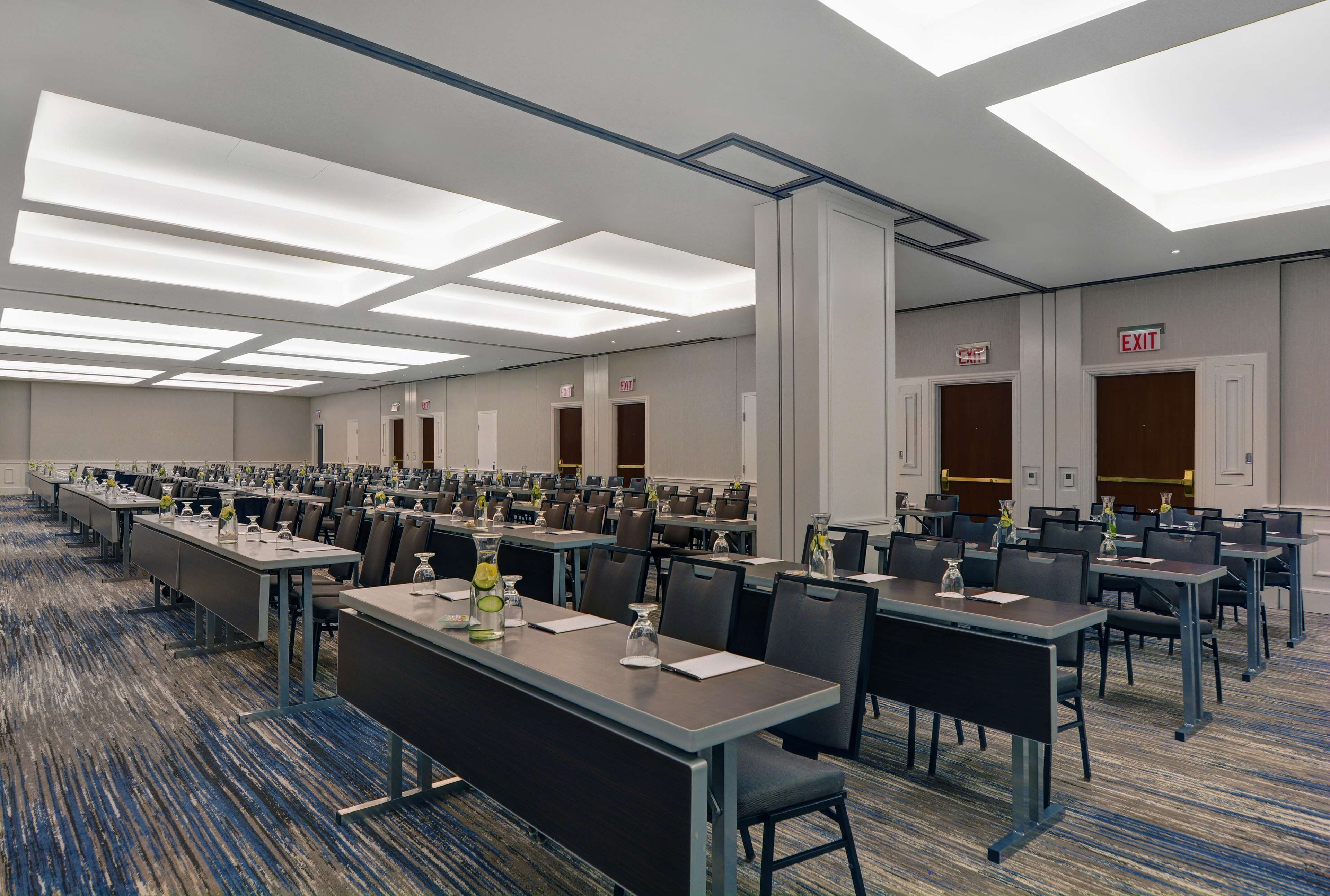 A large conference room with multiple tables and chairs, equipped with nameplates and water bottles.