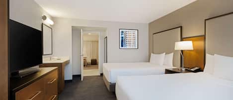 Una habitación de hotel con televisión, dos camas, un escritorio y baño.