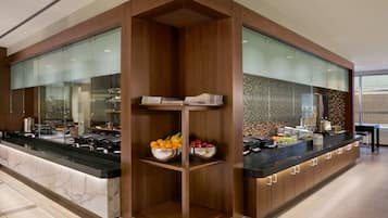 Cocina moderna con encimera de mármol, armarios de madera y una isla central con fruteros.
