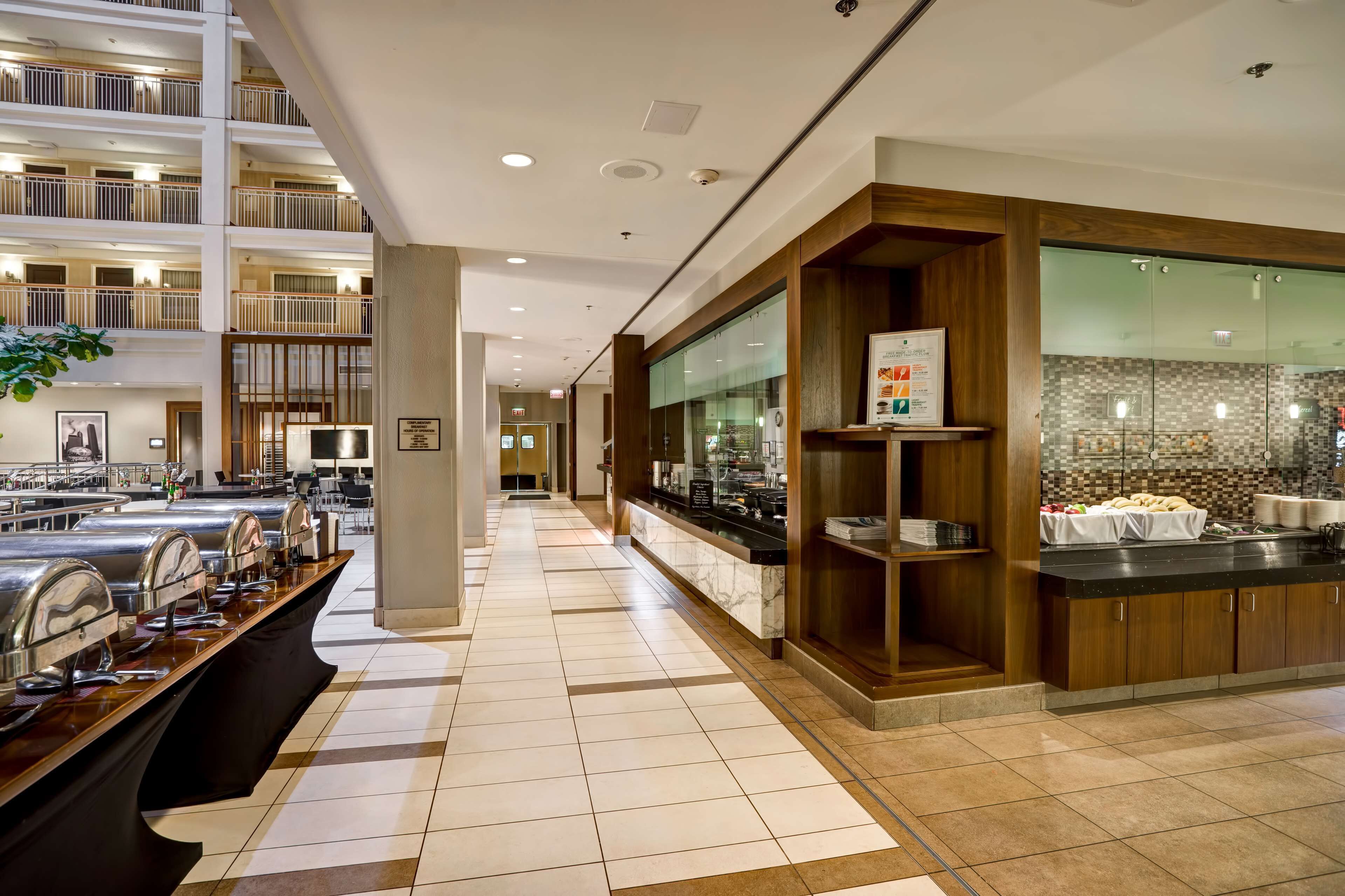 Un moderno vestíbulo de hotel con zona de buffet, cocina y balcón de varios niveles.