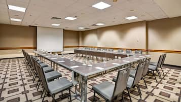Una sala de conferencias con una larga mesa, varias sillas y suelo alfombrado.
