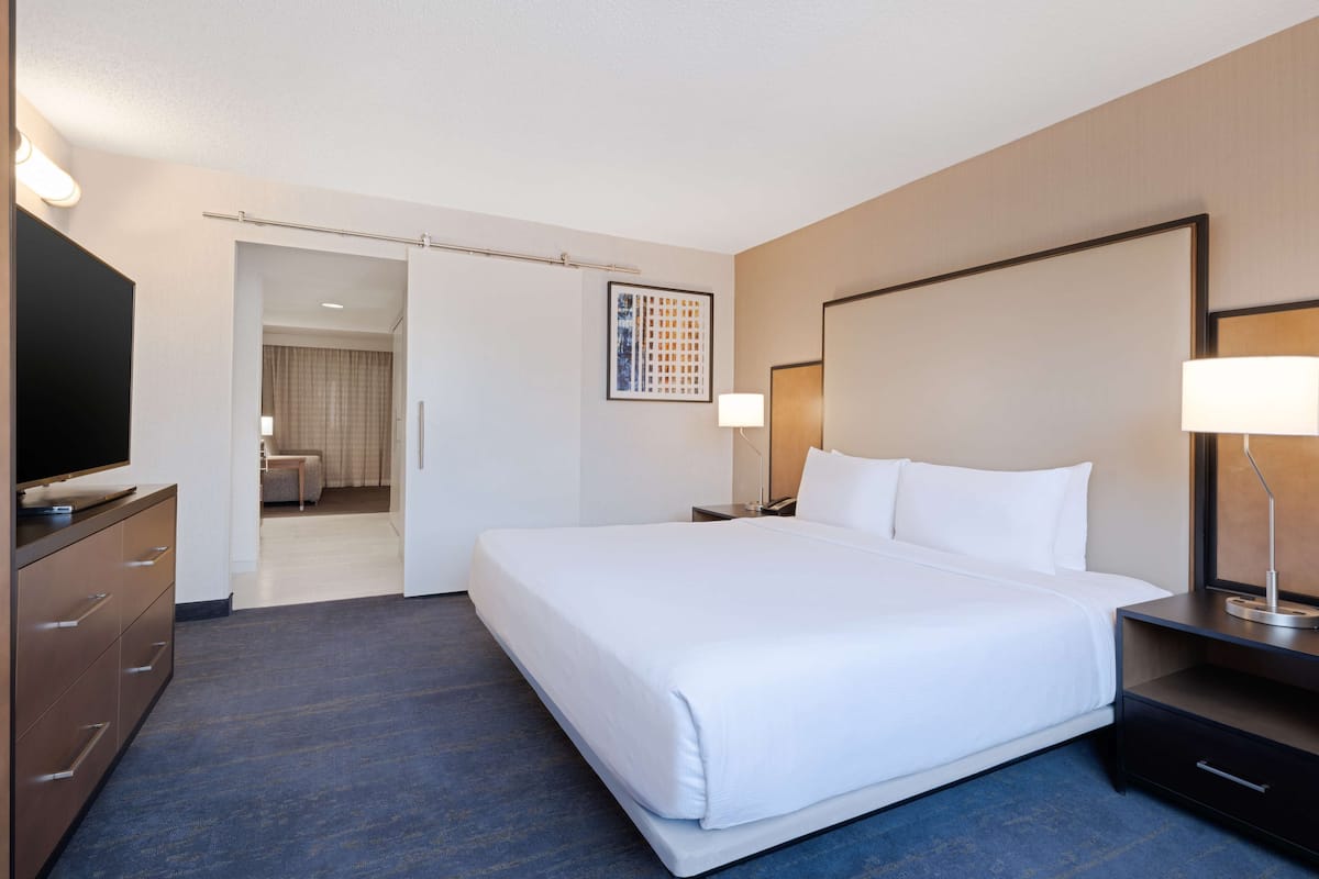 A hotel room with a large bed, a TV, a desk, and a chair.