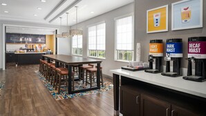 Une cuisine moderne dotée d’un îlot central, de tabourets de bar et d’un coin café avec des distributeurs étiquetés.