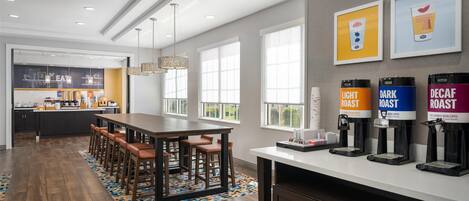 A modern kitchen with a central island, bar stools, and a coffee station with labeled dispensers.