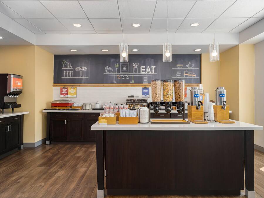 A modern coffee shop with a central island, coffee machines, and a chalkboard menu.