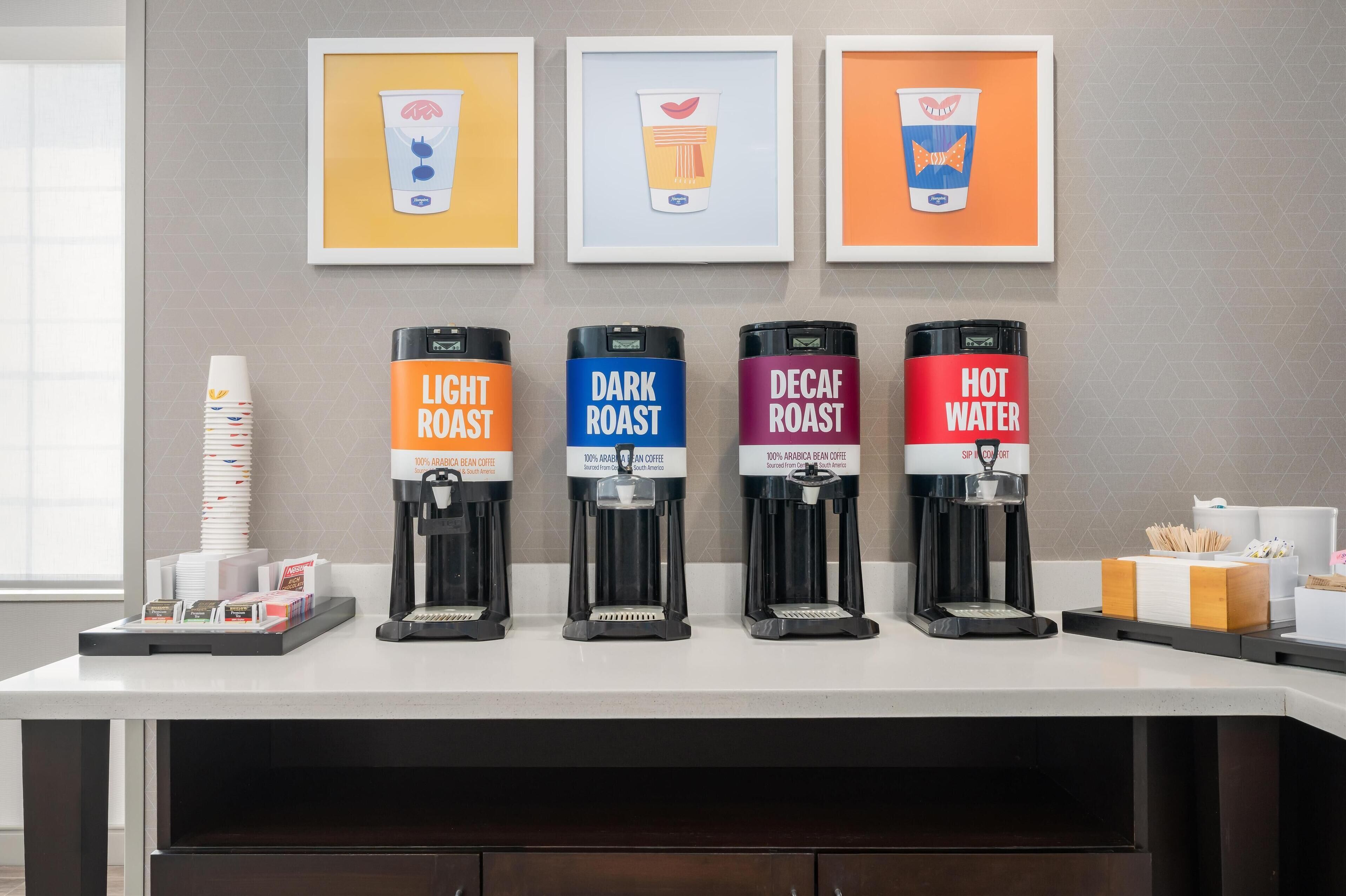 A coffee station with four coffee dispensers labeled Light Roast, Dark Roast, Decaf Roast, and Hot Water.