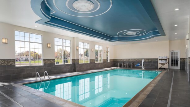 Une grande piscine intérieure dotée d’un plafond au design moderne, de grandes fenêtres et d’une vue sur l’extérieur.