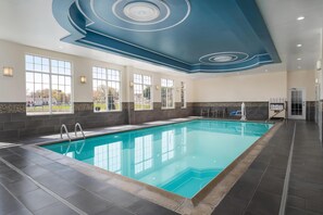 A large indoor swimming pool with a modern ceiling design, large windows, and a view of the outdoors. - Hampton Inn Pawtucket (Pawtucket)