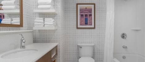 A bathroom with a white sink, wooden vanity, a toilet, and a bathtub.