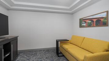 A modern living room with a sofa, a TV, and a framed picture on the wall.