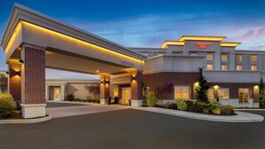 Un hôtel Hampton Inn au design moderne, doté d’une entrée imposante et d’une façade bien éclairée.