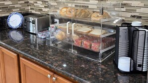 Un bufé de desayuno con distintos alimentos, un tostador y una cafetera.