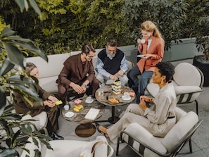 A group of people seated around a table outdoors, engaged in conversation. - Pullman Bucharest (Bucharest)