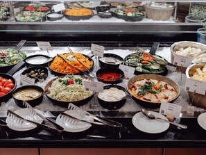 A buffet with various dishes and utensils on a black counter.