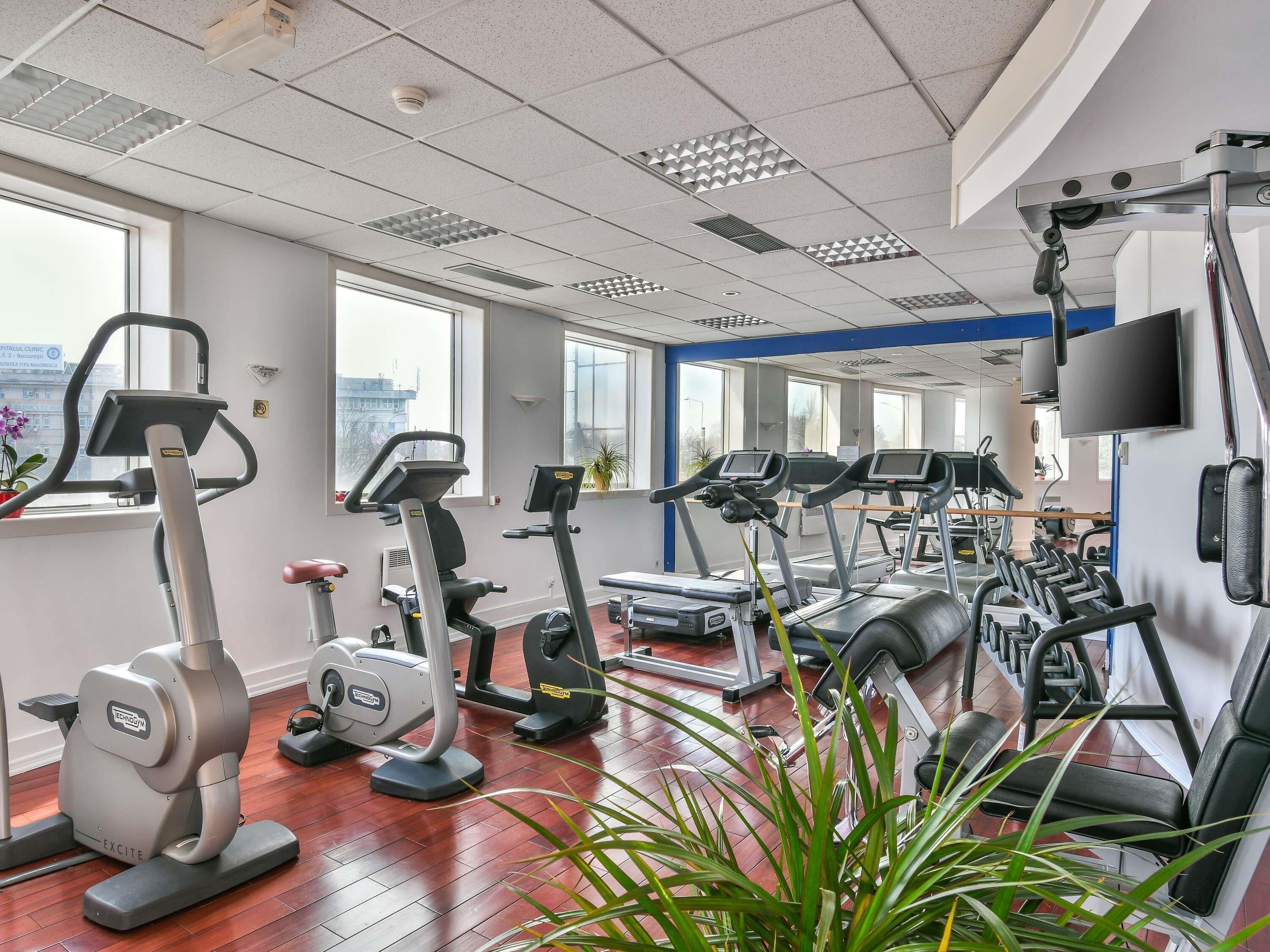 Et fitnessrum med løbebånd, crosstrainere og en motionscykel.