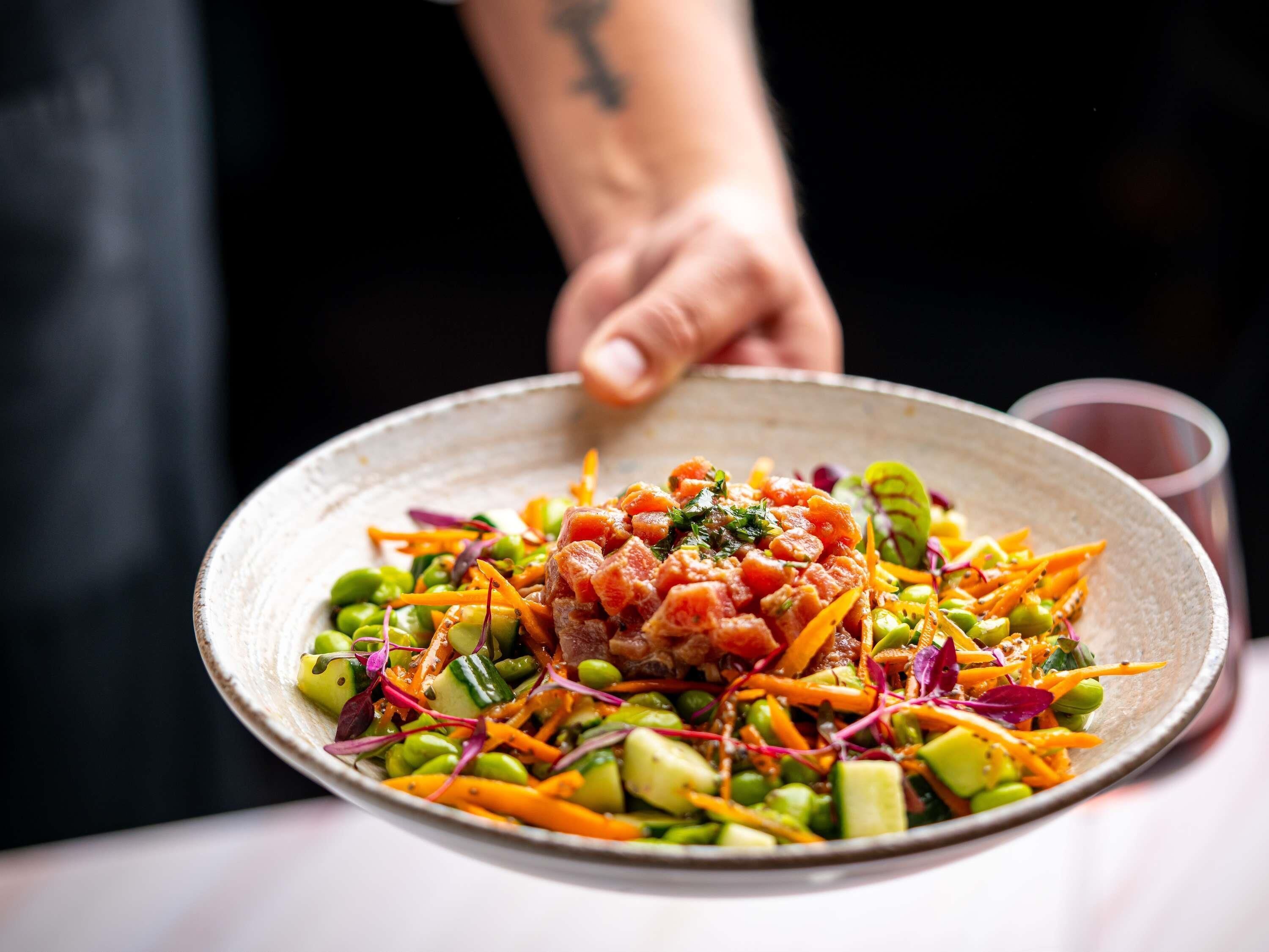 Un plato de comida con varias verduras y una guarnición encima.