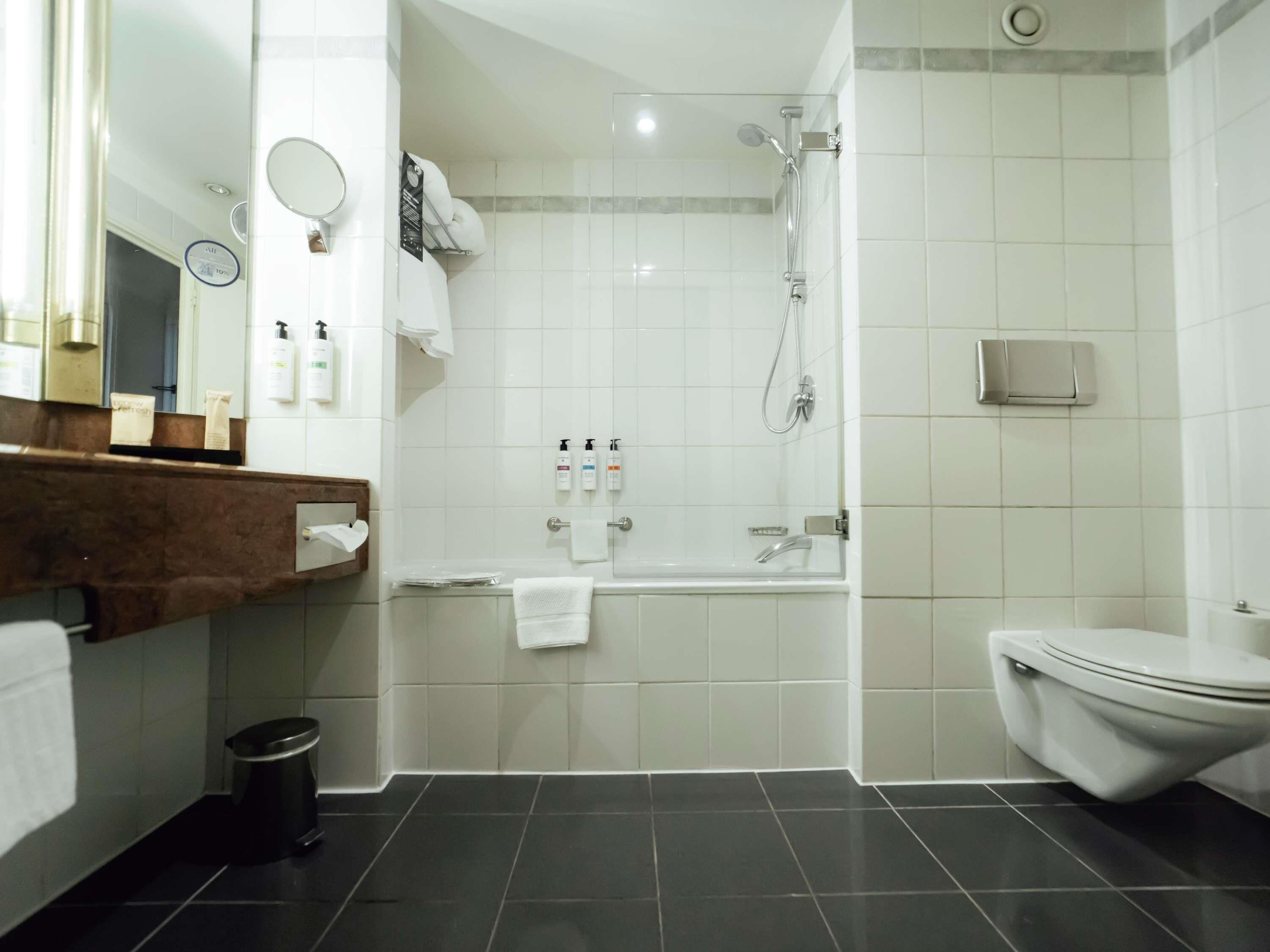 A modern bathroom with a bathtub, toilet, and shower.