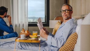 A hotel room with a bed, a tray with breakfast items, and a window with a view. - Pullman Bucharest (Bucharest)