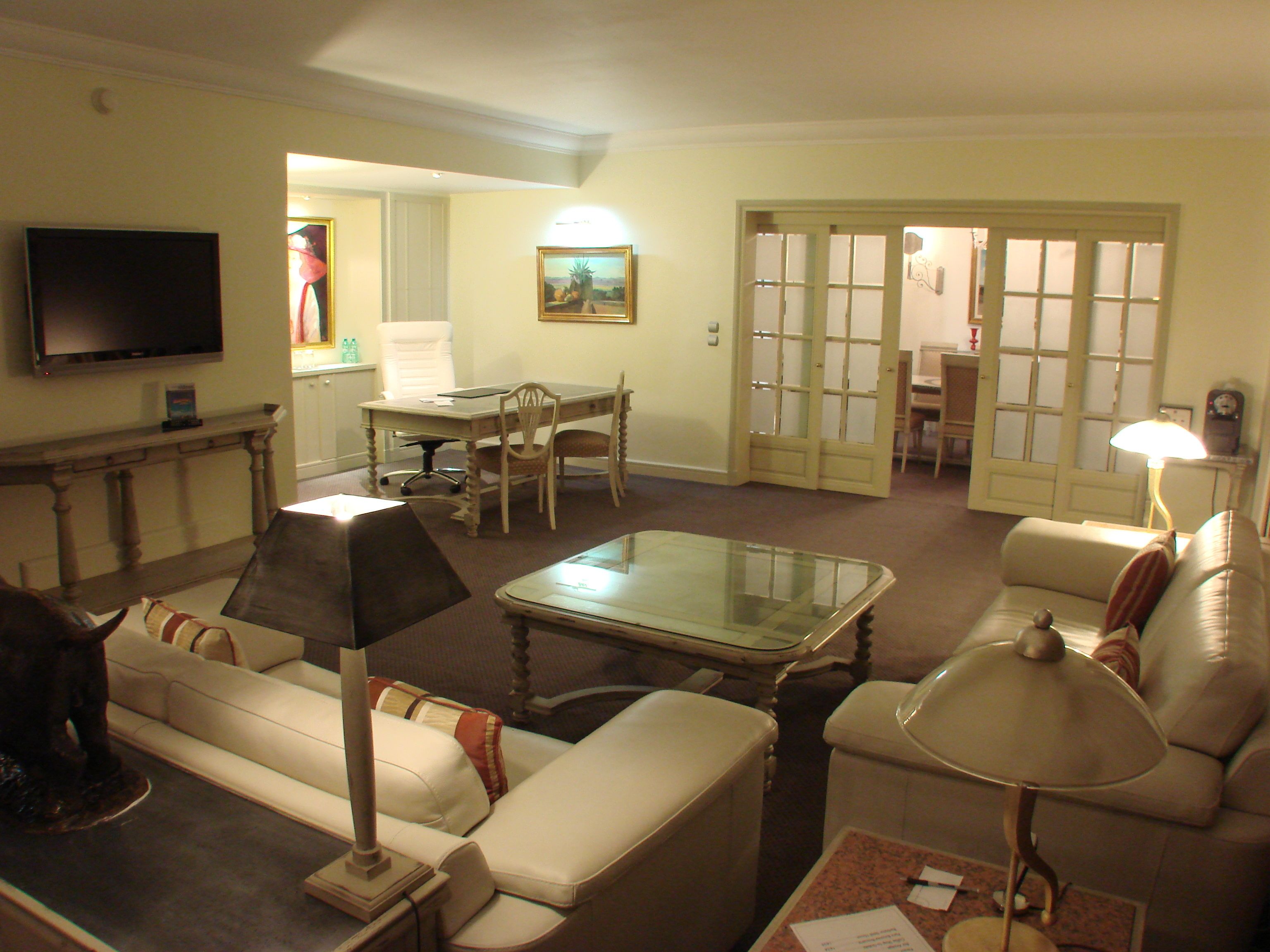 Una sala de estar con sofá, mesa de centro, televisor y un comedor con mesa y sillas.