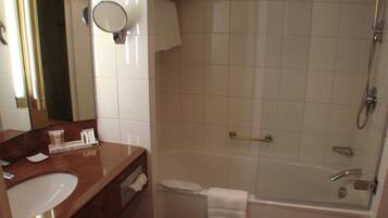 Une salle de bain équipée d’un lavabo, d’un miroir, d’un porte-serviettes et d’une douche séparée par des parois en verre.