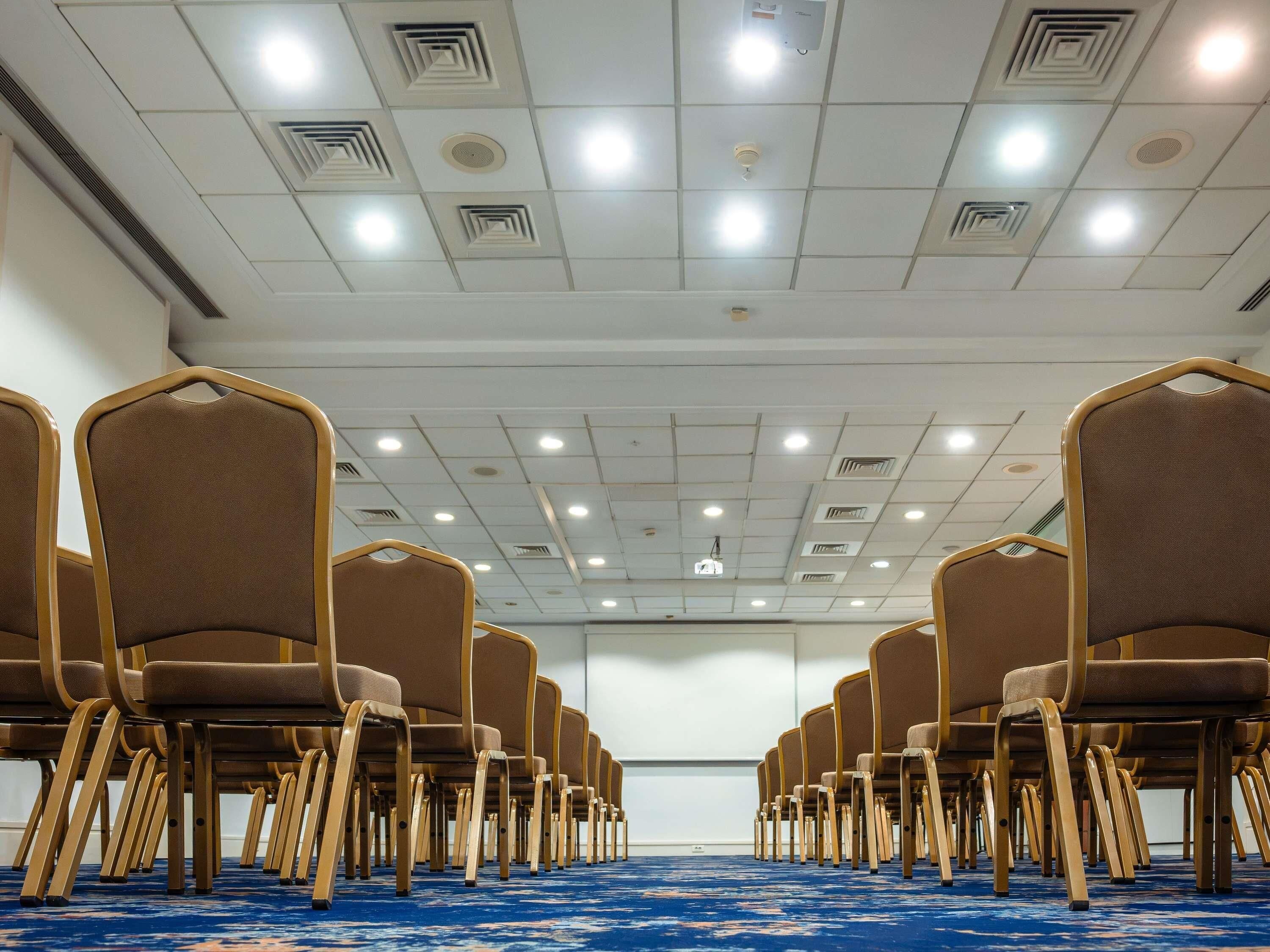 A conference room with rows of chairs and a blue carpet.