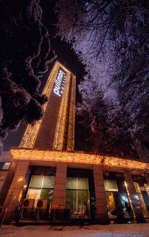 A hotel with a prominent vertical sign, large windows, and a snow-covered ground. - Pullman Bucharest (Bucharest)