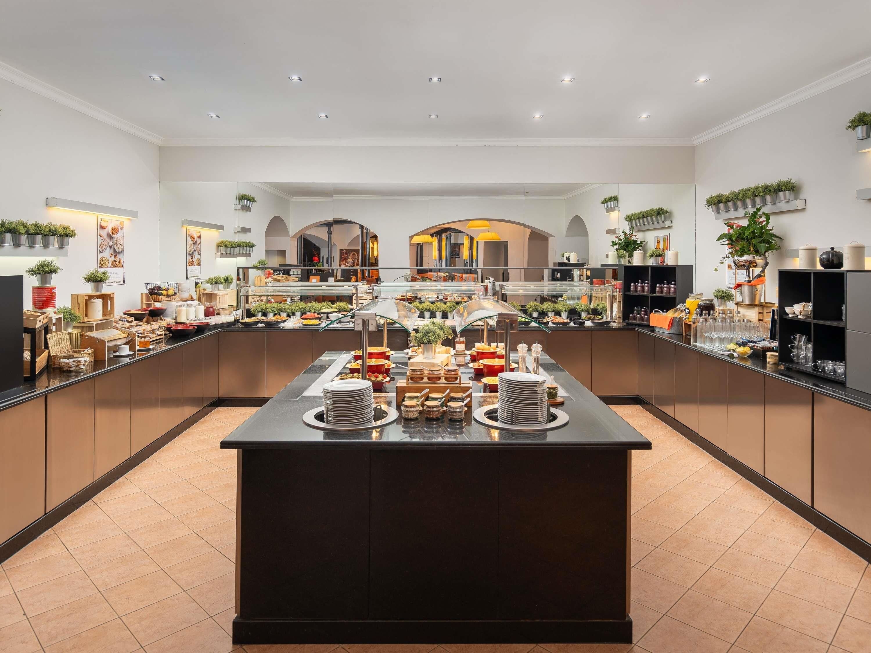 Disposição moderna de buffet, com ilha central, vitrines de vidro e diversas opções de comida.