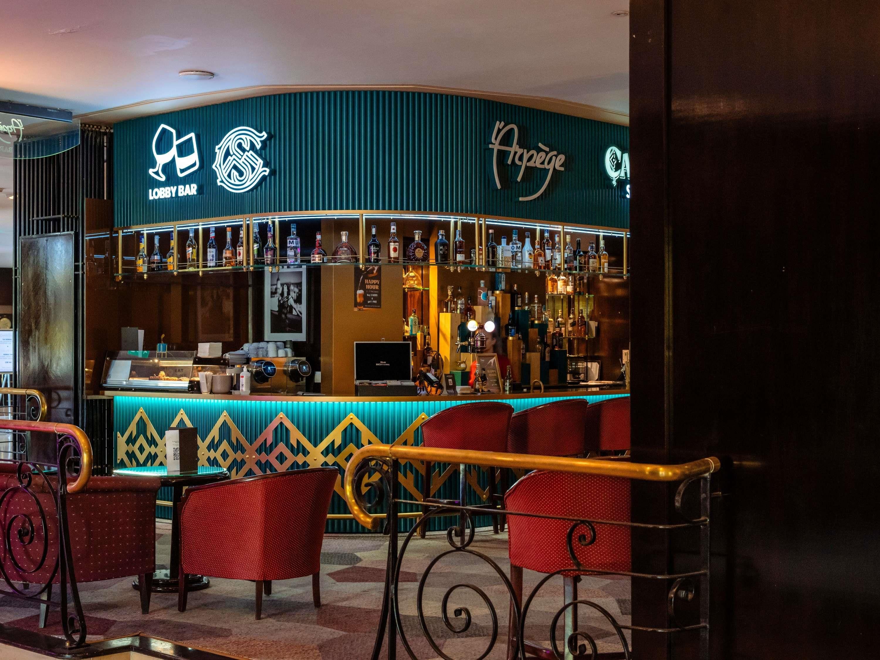 A bar area with a counter, seating, and a variety of bottles.