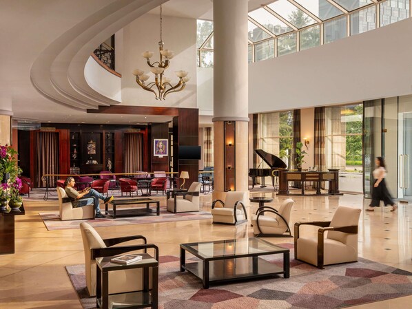 A spacious lobby with a grand chandelier, a piano, and comfortable seating areas.